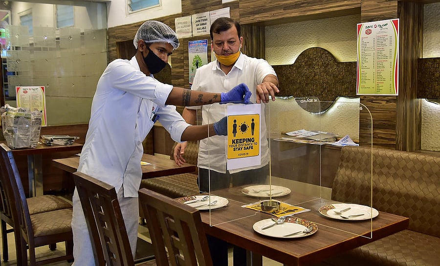 Staff at a hotel put up fibre partitions as dine-in services resume on Monday. DH file/Ranju P