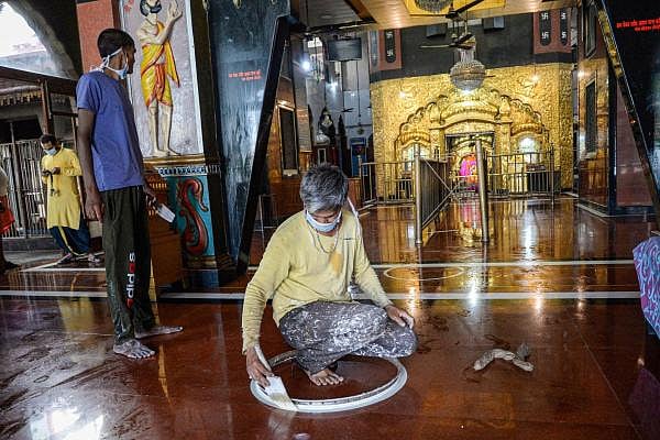 A worker paints circles to help in maintaining social distancing at Kali Mata temple on the eve of its re-opening, during the ongoing COVID-19 lockdown, in Jalandhar, Sunday, June 7, 2020. Credit: PTI Photo