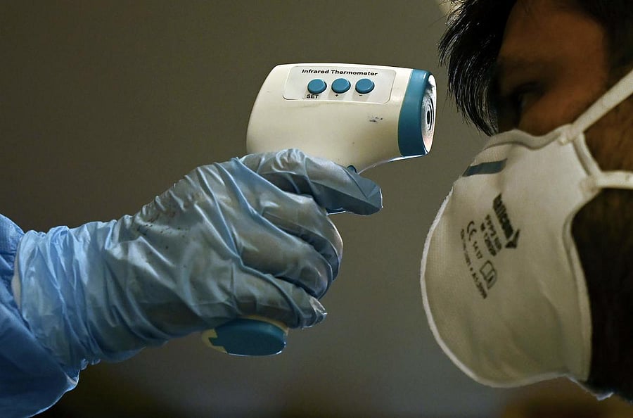 A doctor checks the body temperature of migrant workers (AFP Photo)