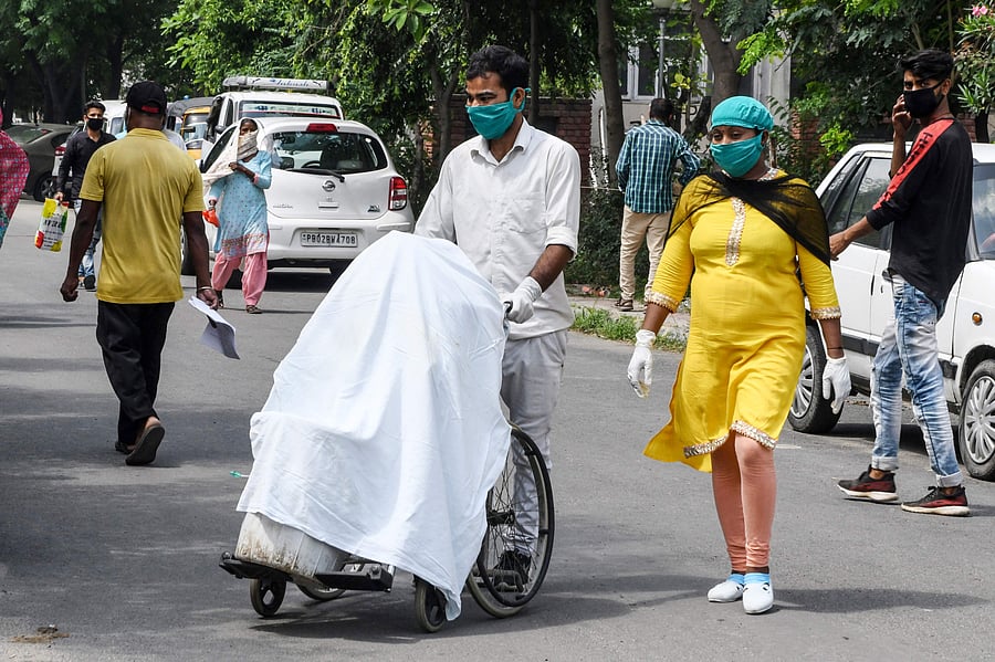 A cleaning staff member (L) carries dustbins filled with medical rubbish on a wheelchair to dump into a large trash bin at Guru Nanak Dev Hospital after the government eased a nationwide lockdown imposed as a preventive measure against the COVID-19. Credits: AFP Photo