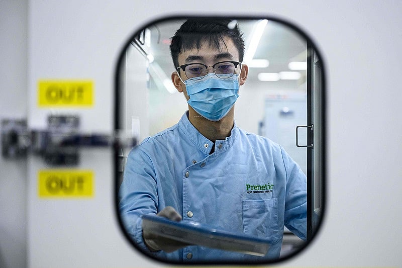 An employee handles a sample at a laboratory of biotech start-up Prenetics/Circle DNA in Hong Kong. Credits: AFP Photo