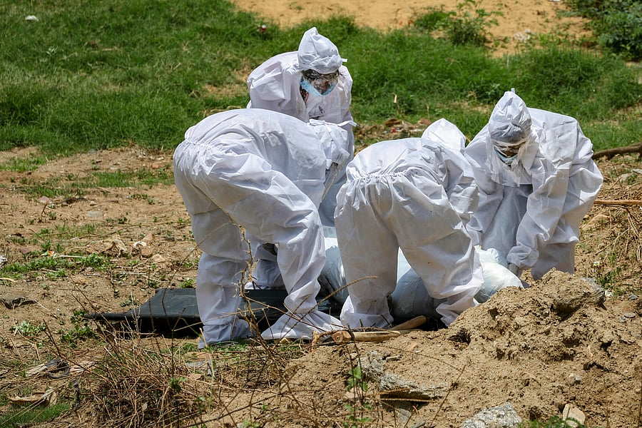Municipal workers, in protective suits, bury the body of a man who died of COVID-19. Credits: PTI Photo