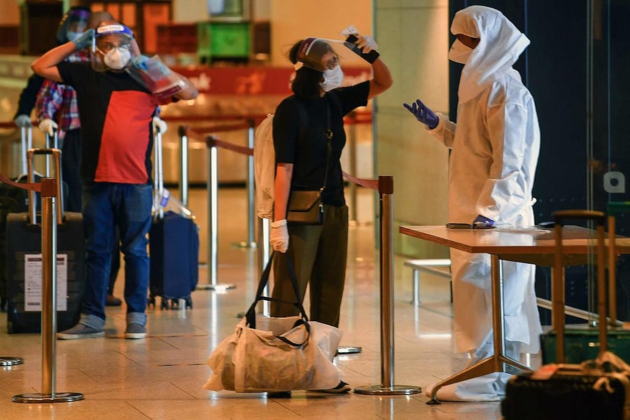 A health worker wearing Personal Protective Equipment (PPE) interacts with an arriving passengers at the Chhatrapati Shivaji Maharaj International Airport (CSMIA) after domestic flights resumed, in Mumbai on May 28, 2020.  Credit/AFP Photo