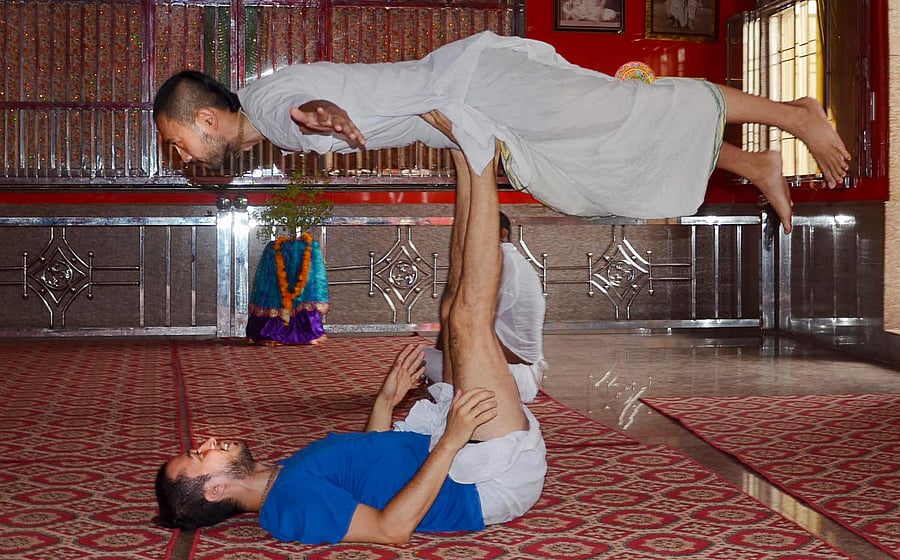 Foreign and local devotees perform 'yoga' in a temple on the occasion of International Day of Yoga, in Mathura, Sunday, June 21, 2020. Credit/PTI Photo