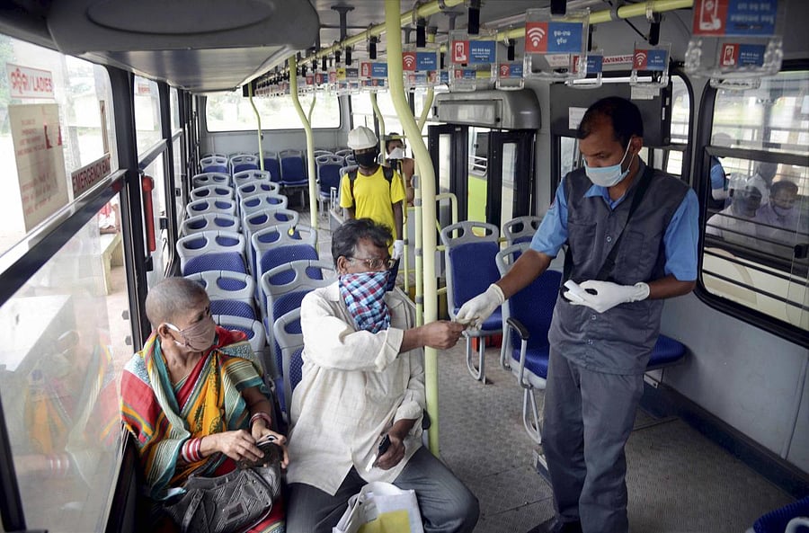 A bus conductor collects fare from passengers travelling to Cuttack by 'Mo Bus service', during the ongoing COVID-19 lockdown, in Bhubaneswar, Tuesday, May 26, 2020. Credit/PTI Photo