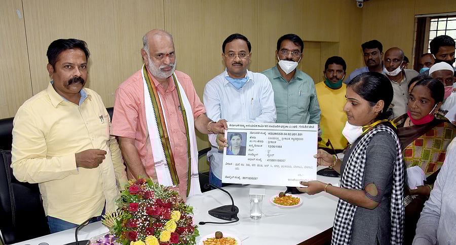 Labour Minister Shivram Hebbar symbolically distributing identity cards to the workers from unorganised sector in Belagavi on Monday. (DH Photo)