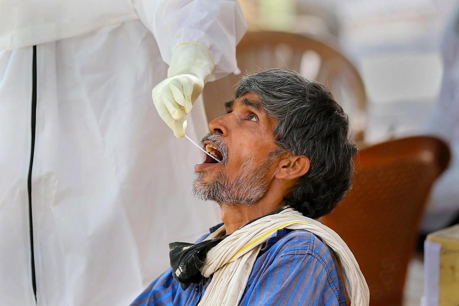 A medic collects swab sample of an elderly homeless man for the COVID-19 test, in Jaipur, Monday, June 22, 2020. Credit/PTI Photo