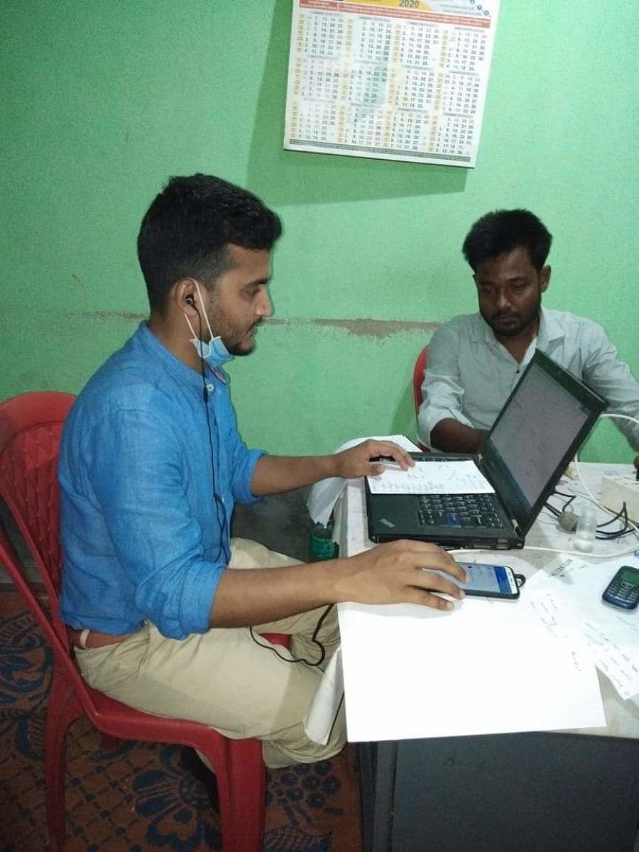 Sadekul Islam (in blue shirt) working at his temporary office to help migrant workers. Photo by special arrangement