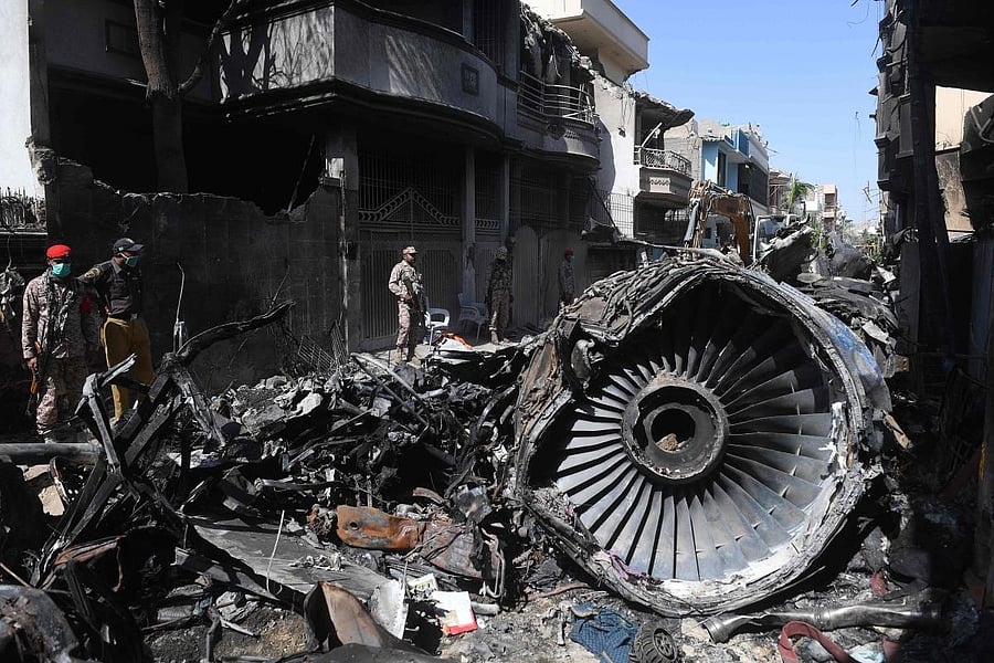  In this file photo taken on May 24, 2020, security personnel stand beside the wreckage of a plane at the site after a Pakistan International Airlines aircraft crashed in a residential area days before, in Karachi. Credit: AFP