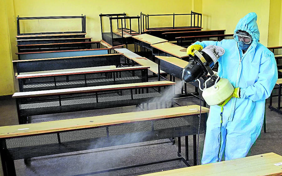 A health worker sprays disinfectant in a classroom in Karnataka Public School, Malleswaram, Bengaluru on Tuesday where SSLC examination will be held from June 25. DH Photo