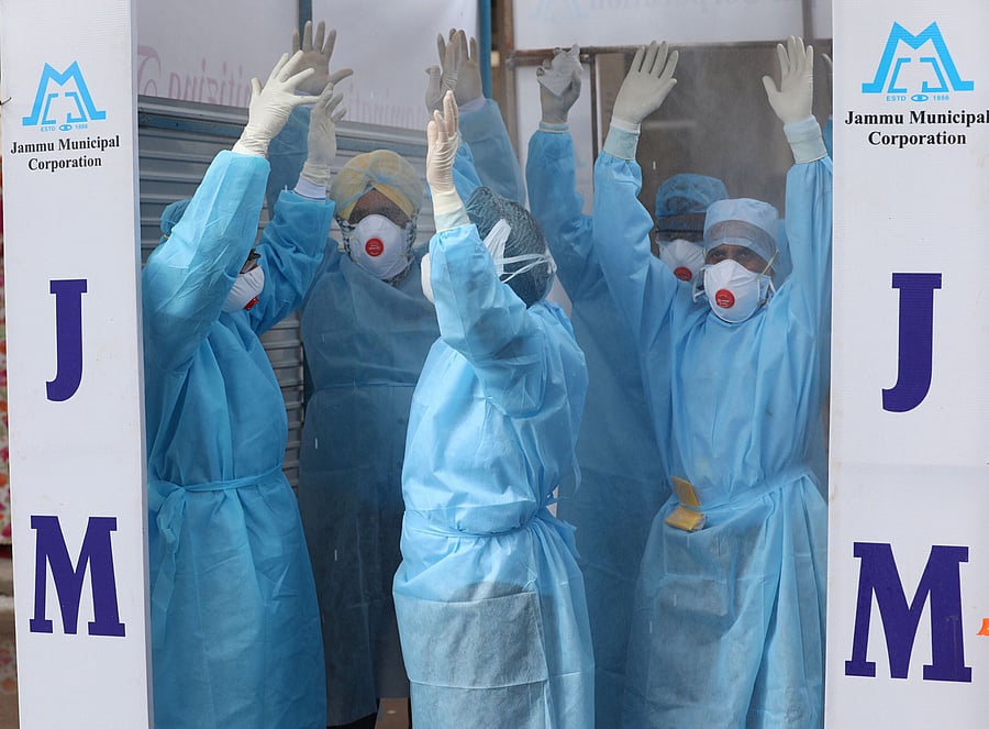 Paramedical staff members are seen inside a full body sanitizing machine outside Government Medical College where coronavirus-affected patients are being treated. Credit: PTI