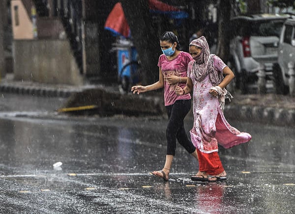 Women cross a road during pre-Monsoon rainfall, in New Delhi, Wednesday, June 24, 2020. Credit: PTI Photo