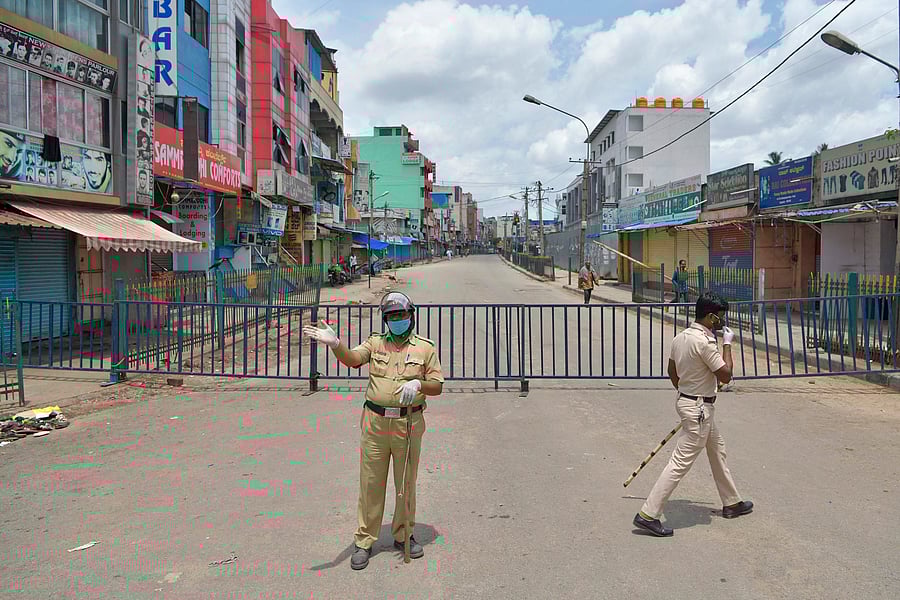 A policeman gestures in front of a barricaded commercial street lined with shops and business establishments, which was closed by the authorities in Bangalore on June 25, 2020 as COVID-19 coronavirus cases continue to rise. - With a population of 1.3 billion, India is the fourth worst-hit country in the world with more than 425,000 infections, official figures show. (Photo by AFP)