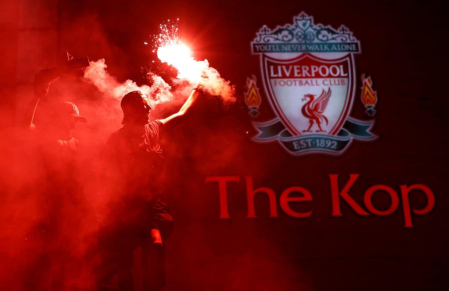  Liverpool fans celebrate winning the Premier League with flares outside Anfield after Chelsea won their match against Manchester City. Credit/Reuters Photo