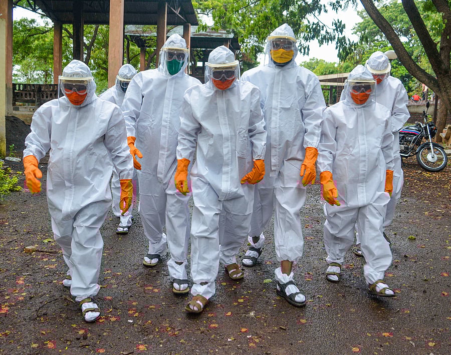 Municipal workers wearing protective suits before cremating the body of a person who died of Covid-19 at a crematorium, during the ongoing nationwide lockdown. Credits: PTI Photo