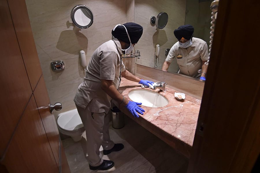 In this picture taken on June 19, 2020, a housekeeping employee of the Suryaa hotel cleans a bathroom in New Delhi. Credit/AFP Photo