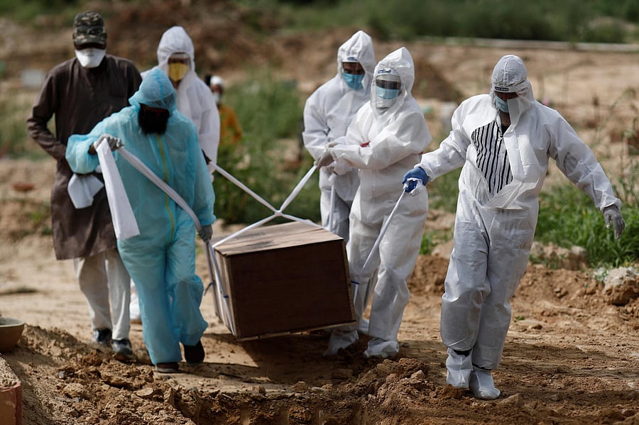 Relatives wearing Personal Protective Equipment (PPE) carry a coffin with a body of a person who died from Covid-19 at a graveyard in New Delhi. Reuters
