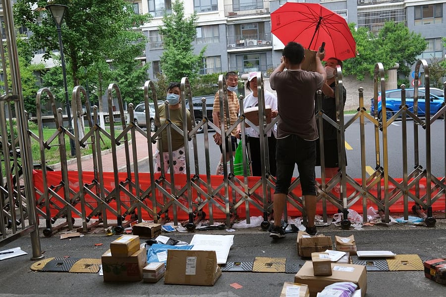 A delivery worker passes a parcel to a resident over a closed entrance to a residential compound, following the outbreak of the coronavirus, in Beijing. Reuters