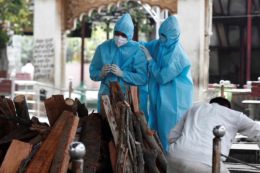 Relatives wearing protective gear mourn a man who died due to the coronavirus disease (COVID-19), at a crematorium in New Delhi. Credit: Reuters