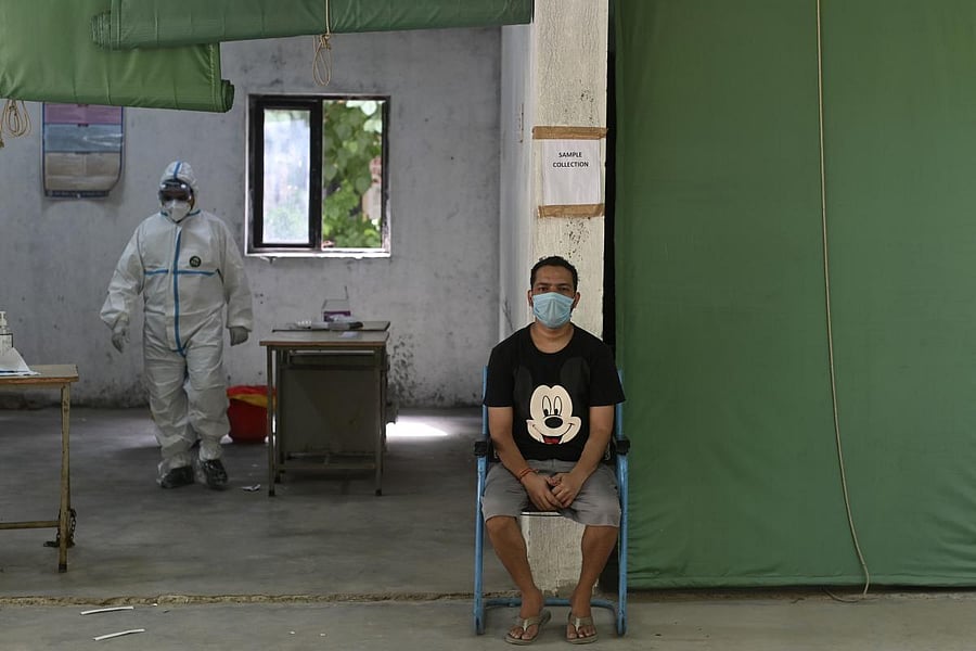 A medical staff (L) wearing personal protective equipment (PPE) walks to collects a rapid antigen test (RAT) for the COVID-19 coronavirus at a testing centre, after the government eased a nationwide lockdown as a preventive measure against the COVID-19 coronavirus, in New Delhi on June 29, 2020. Credit/AFP Photo