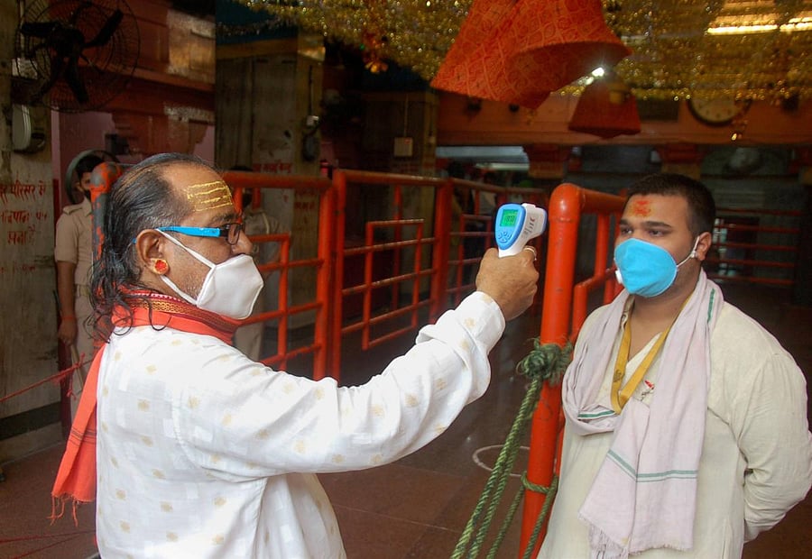 A priest undergoes temperature scanning as he arrives for service at the Vindhyavasini temple, in Mirzapur, Monday, June 29, 2020. The temple was reopened after a gap of 100 days, owing to COVID-19 pandemic. (PTI Photo)