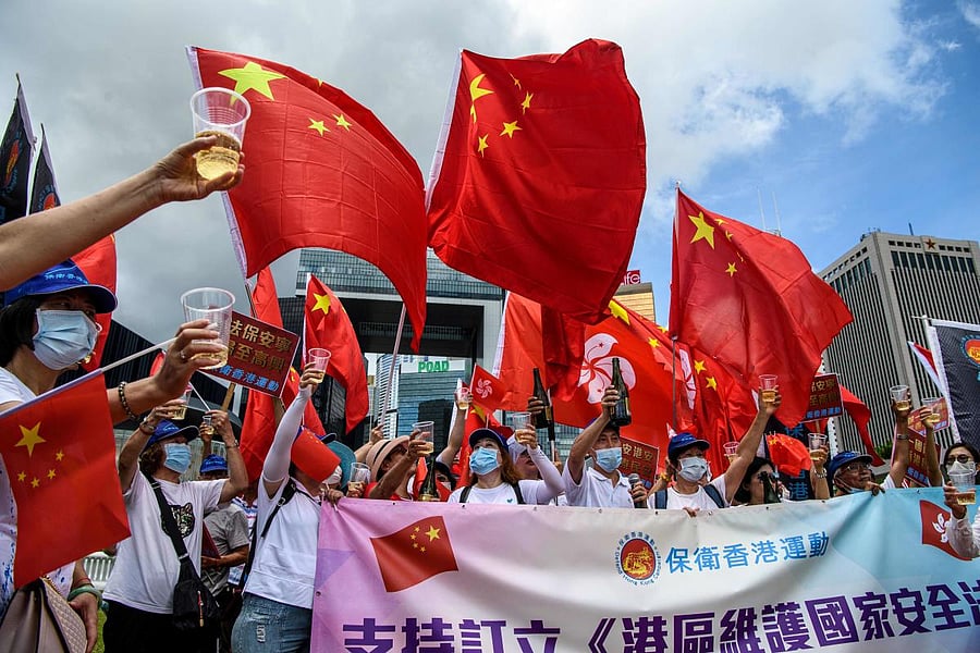 Pro-China supporters display Chinese and Hong Kong flags as they raise a toast with champagne during a rally near the government headquarters in Hong Kong on June 30, 2020, as China passed a sweeping national security law for the city. Credit/AFP Photo
