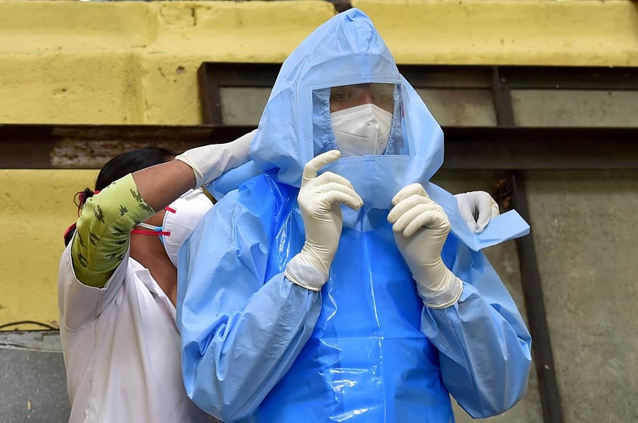 A medic helps her collegue wear a PPE before collecting samples for Covid-19 swab testing at Halasuru Gate traffic police station, during Unlock 2.0, in Bengaluru (PTI Photo)