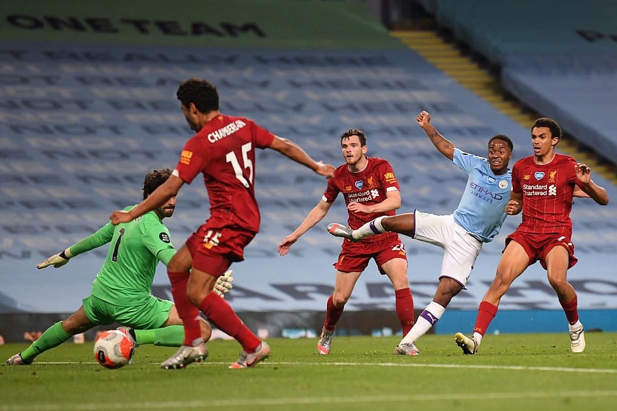 Manchester City's English midfielder Raheem Sterling (2nd R) watches his shot beat Liverpool's Brazilian goalkeeper Alisson Becker (L) and deflect off Liverpool's English midfielder Alex Oxlade-Chamberlain (2nd L) for an own-goal to make it 4-0 during the English Premier League football match between Manchester City and Liverpool at the Etihad Stadium in Manchester, north west England, on July 2, 2020. Credit/AFP Photo