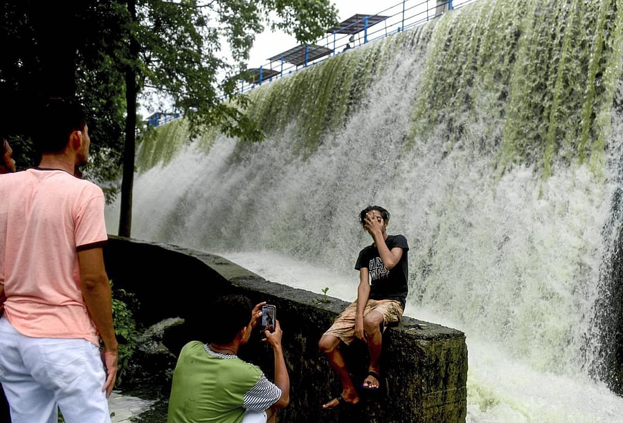 A boy poses for a photo in the backdrop of Powai lake overflowing due to heavy rain, in Mumbai, Sunday, July 5, 2020. (PTI)