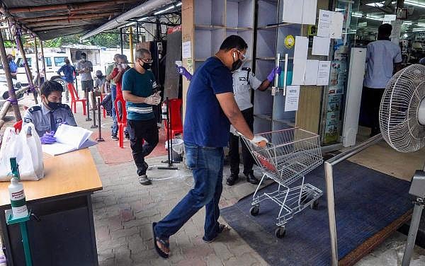 People maintain social distancing as they wait outside grocery shops, during total lockdown imposed by the Assam Government. Credit: PTI