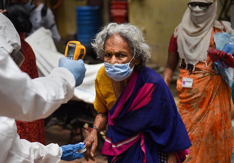  A health worker scans temperature of an elderly woman while conducting door-to-door medical check-up of the residents of Dharavi slum, amid Covid pandemic in Mumbai, Thursday, July 9, 2020. Credit: PTI Photo