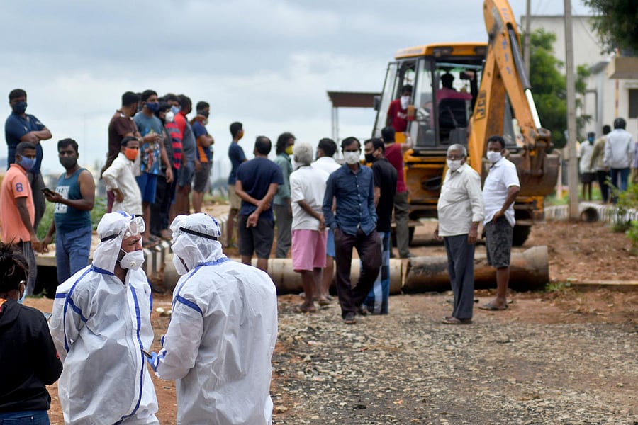 Residents of M S Palya argue with the health workers as they protest against the cremation of a Covid-19 victim's body in their area, in Bengaluru. Credit: DH Photo by Pushkar V