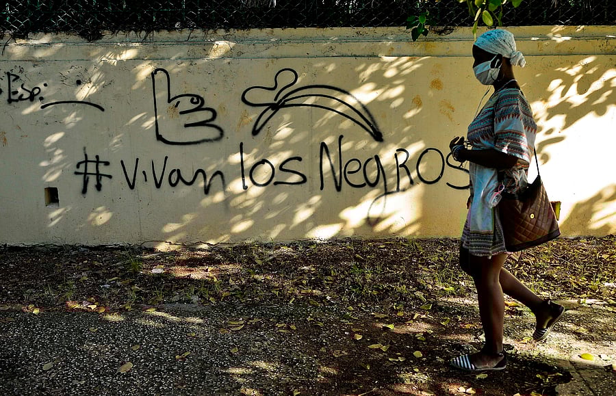 An Afro-Cuban woman wearing a face mask as a preventive measure against the spread of the novel coronavirus, COVID-19, walks past a graffiti reading "Long Live Black People" in Havana. Credits: AFP Photo