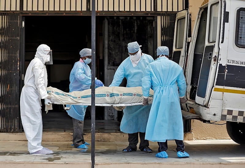 Municipal workers in protective gear carry the body a woman who died due to coronavirus disease. Credit: Reuters Photo