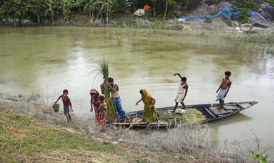 Flood affected villagers move to a safe place from the flooded locality in Morigaon district of Assam. Credit: PTI