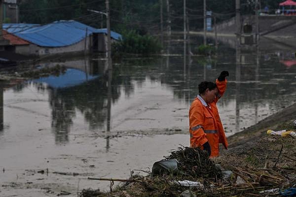 A woman gestures as she cleans a residential affected area by the rising water level of the Yangtze river is seen in Jiujiang, in China. Credit: AFP