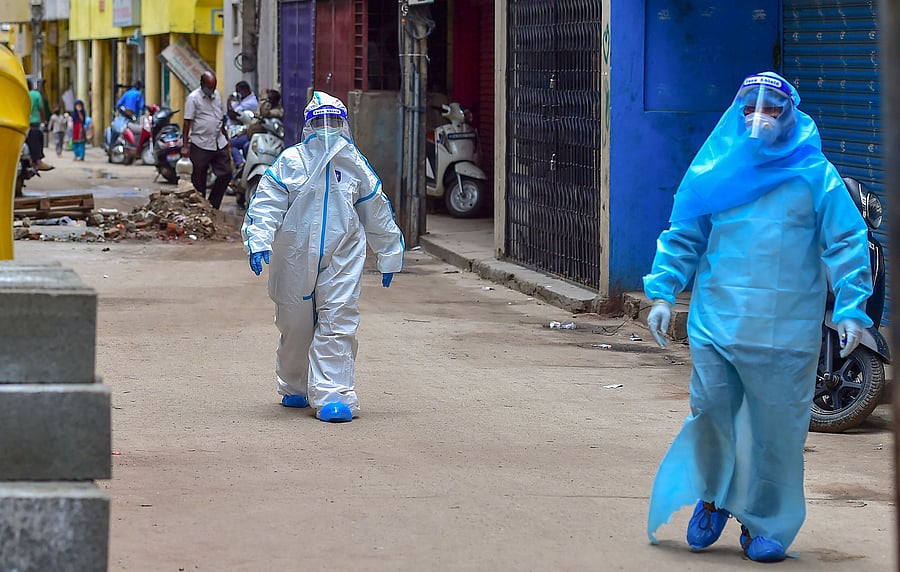 Medics wearing PPE kits arrive to conduct COVID-19 Rapid Antigen test at Kalasipalyam during a week lockdown imposed due to surge in coronavirus. Credits: PTI Photo