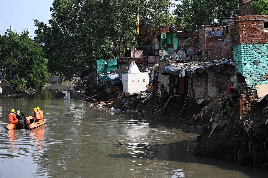 National Disaster Response Force personnel inspect on a dinghy the area where some shanty houses collapsed into a canal due to heavy rains in New Delhi. Credit: AFP