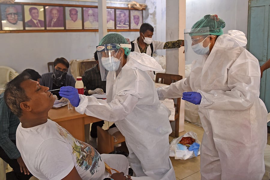 Health workers wearing Personal Protective Equipment (PPE) suits take a swab sample from a man during a medical screening for the Covid-19 coronavirus, in Ahmedabad. Credit: AFP Photo