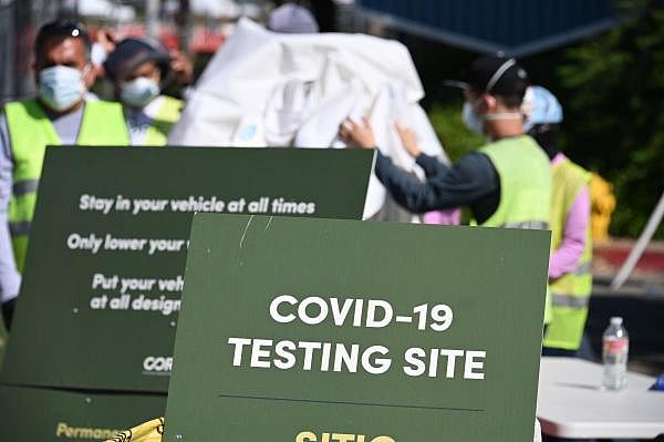 Workers pack up tents at a cornavirus testing site in a parking lot. Credit: AFP