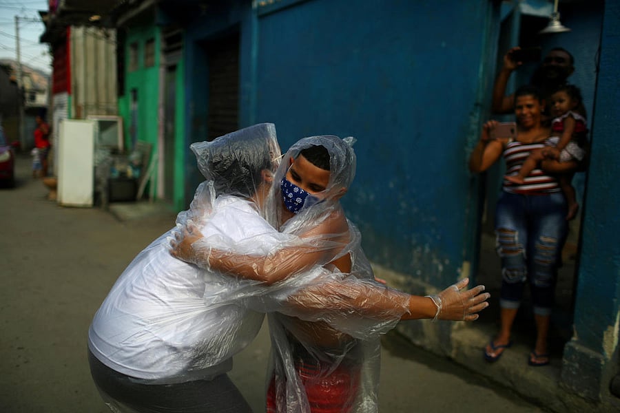 Teacher Maura Silva, who created a "hug kit" using plastic covers, embraces her student Yuri Araujo Silva at Yuri's home, amid the coronavirus disease. Credit: Reuters