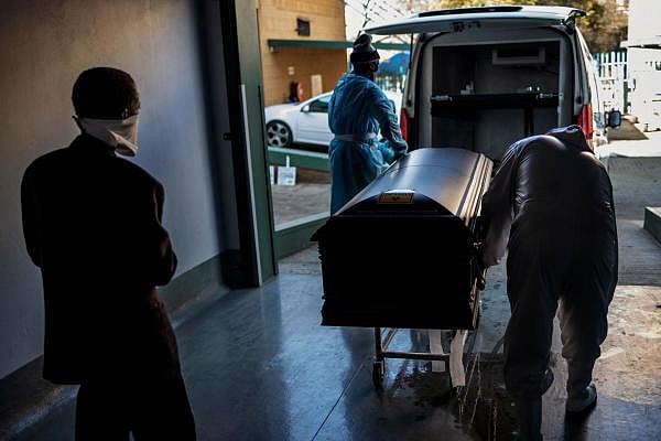 A relative observes undertakers loading a casket containing the remains of a Covid-19. Credit: AFP