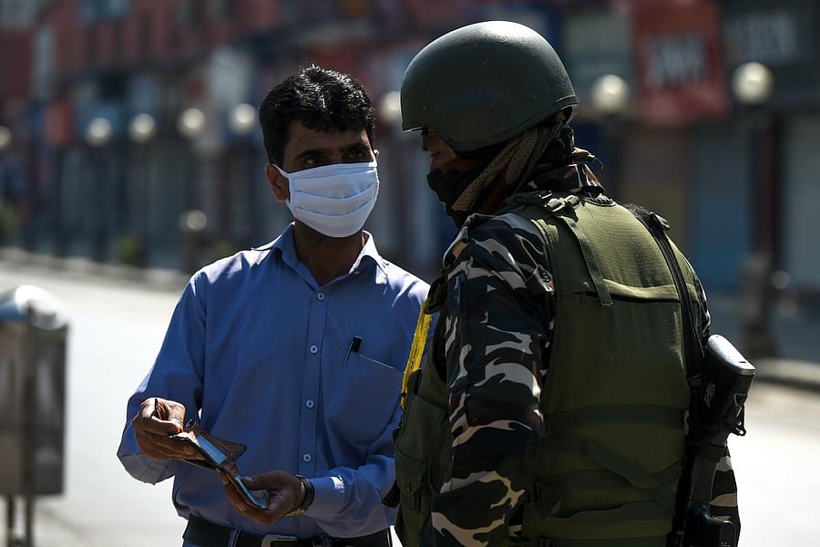 A security personnel (R) checks the identity documents of a pedestrian on a street during a lockdown imposed by the authorities as a preventive measure against the surge in COVID-19 coronavirus cases, in Srinagar on July 23, 2020. Credit: AFP Photo