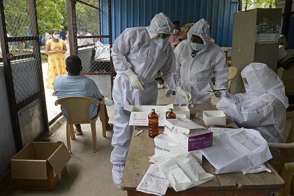 Health workers wearing Personal Protective Equipment (PPE) gear prepare to collect swab samples of residents at a free testing centre for coronavirus, in Hyderabad. Credit: AFP