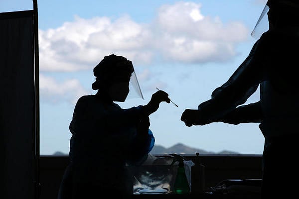 A health worker puts a swab sample from a taxi driver into a container for Covid-19 test at a makeshift testing station in a parking lot following the coronavirus disease. Credit: Reuters