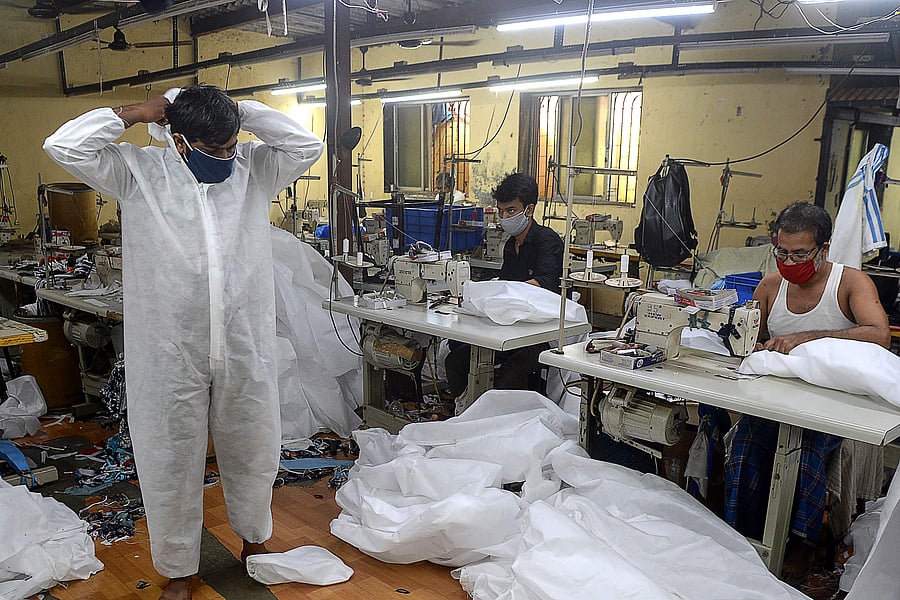 A supervisor inspects one of the finished Personal Protective Equipment (PPE) products at a garment manufacturing unit. Credit: AFP Photo