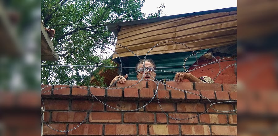 Congress leader and former Union minister Saifuddin Soz climbs up the wall of his house to speak to a media person, in Srinagar. Credit: PTI Photo