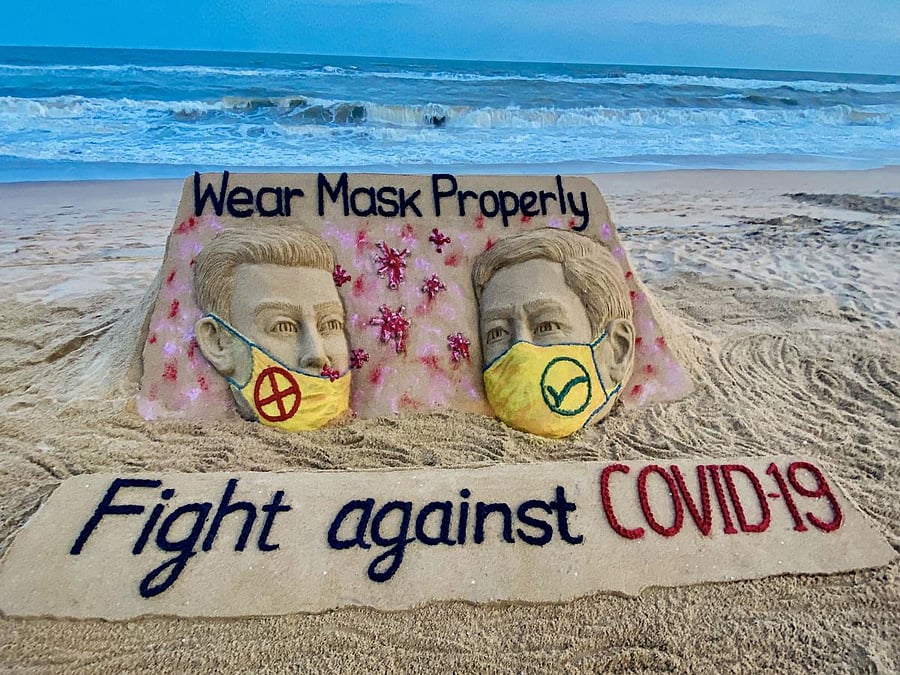 Sand artist Sudarsan Pattnaik created a sand sculpture depicting people wearing protective facemasks with a message reading 'Fight against Covid-19' at Puri beach, Monday, July 20, 2020.