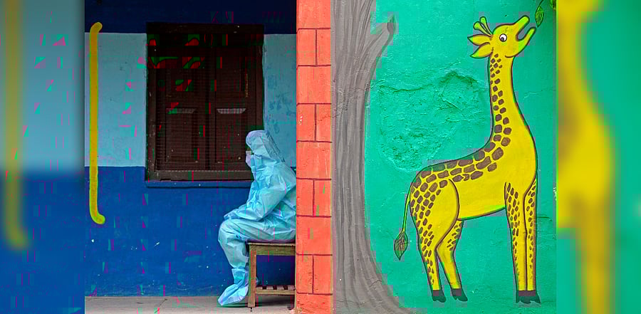 A health worker wearing personal protective equipment (PPE) gear sits at the entrance of a free testing centre for the Covid-19. Credits: AFP Photo