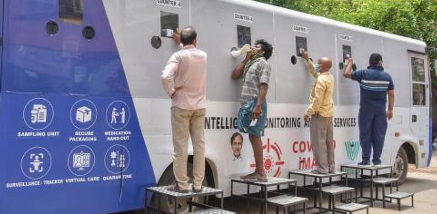 People stand near a Covid-19 mobile testing facility, at Jafarguda near Karwan in the old city of Hyderabad. Credit: PTI Photo